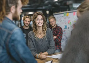 Team bei einer Besprechung vor einem Whiteboard mit Haftnotizen