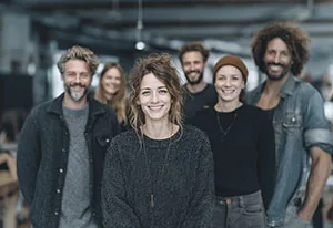 Sechs Personen stehen nebeneinander in einem Loftbüro